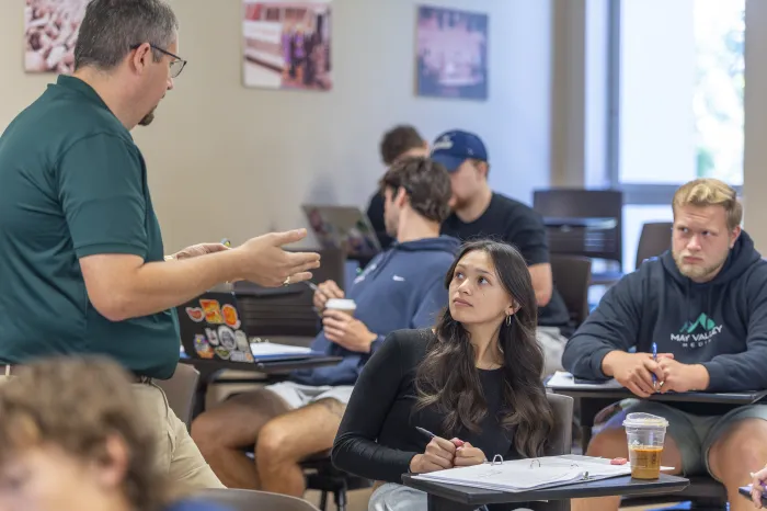 Professor Doug Ankrom speaks with a student in a lecture hall