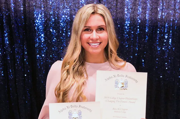 Alpha Xi Delta President Loren Coontz holds up some awards the sorority recently received.