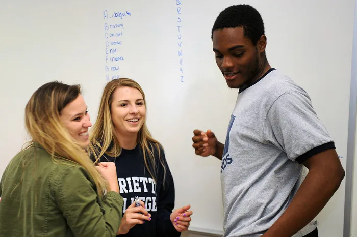 Three entrepreneur students working on a problem at the erase board