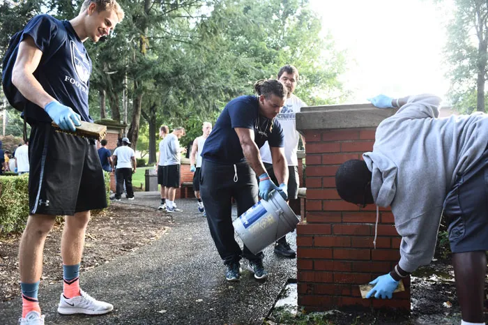 football players scrubbing the Fourth Street gateway