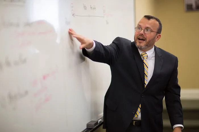 Gama Perruci pointing at a white board