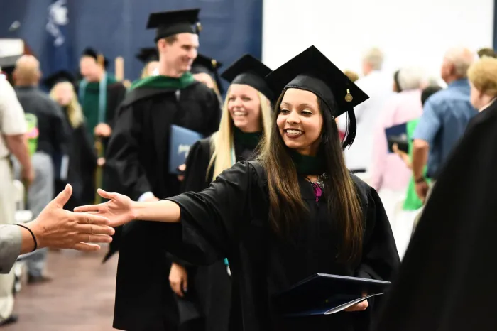 Female student shakes hands after graduating