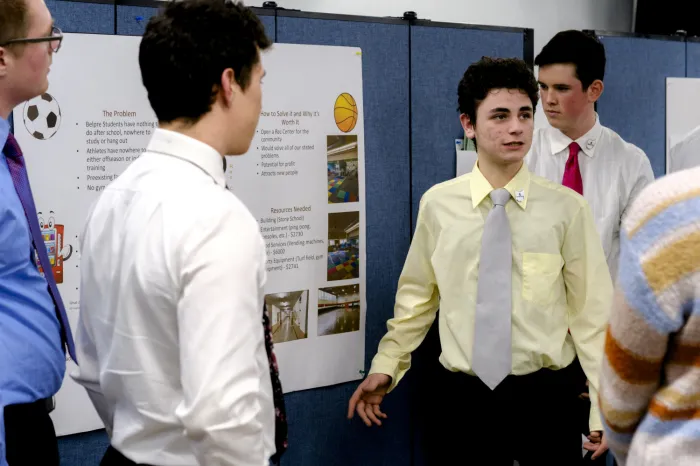 Male high school student wearing ties and dress shirts making a presentation