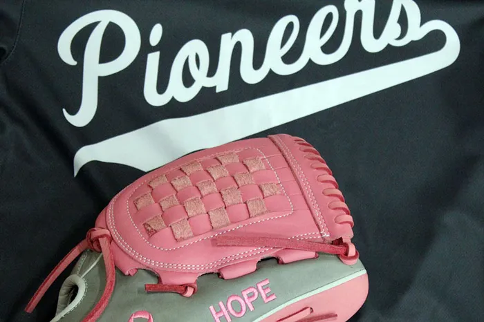 Pink softball glove on top of a softball jersey