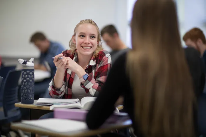 Female student speaking with another student in class