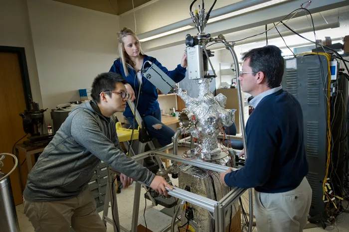 Dr. Dennis Kuhl working with 2 students in physics lab