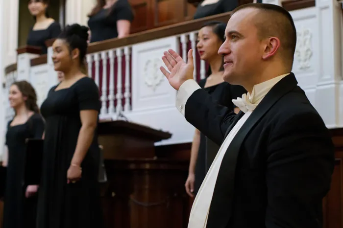 Choral director acknowledging the women's choir after singing