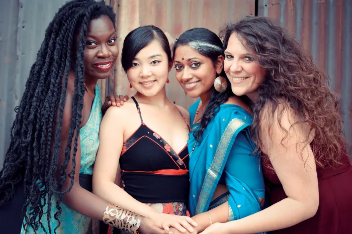 Four women huddled together holding hands