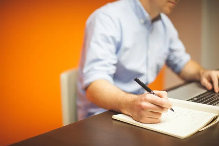 Man writing with one hand and typing with the other