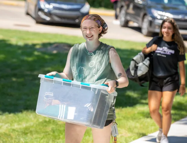 Female student carrying a plastic tub