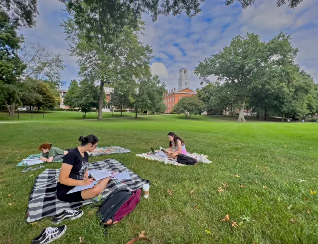 Young women outside studying in the grass