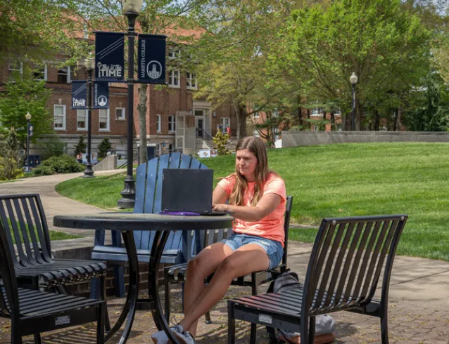 Student seated outside working on her laptop