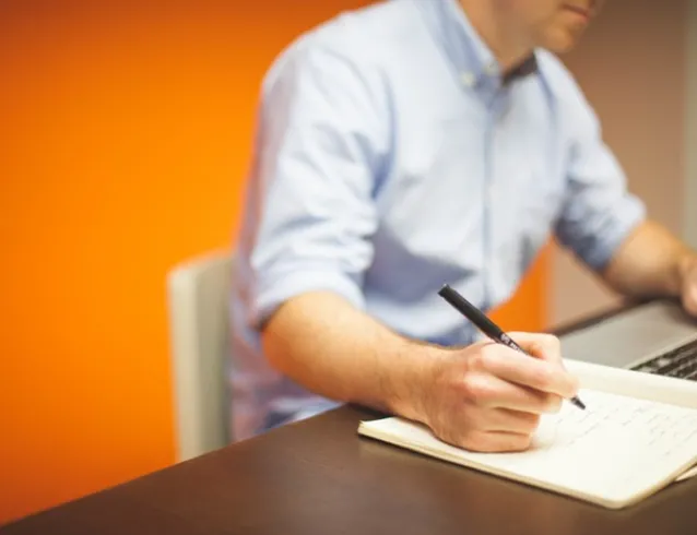 Man writing with one hand and typing with the other