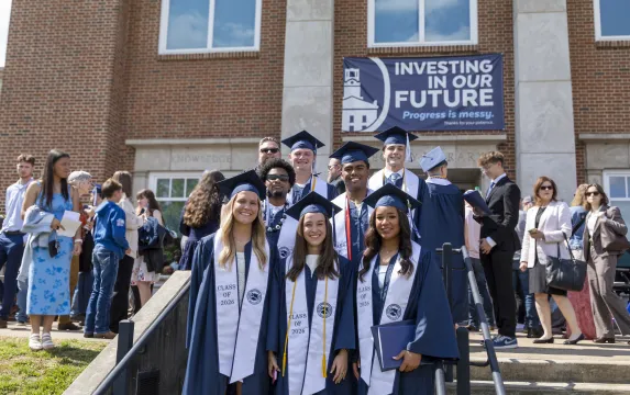 Marietta College graduates stand together happily in front of Legacy Library.