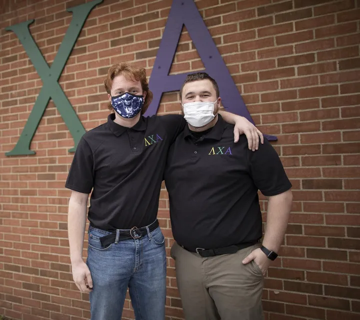 Two Marietta College students stand in front of the Lambda Chi Alpha Sign