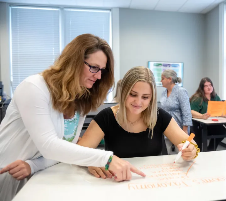 A Marietta College professor of Education works at a table with a student