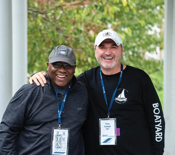 Charles Little ’87 (left) and Terry Tackett ’87 laughing while taking a group picture