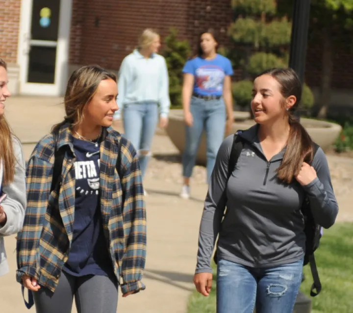 Three women walking in front of the library