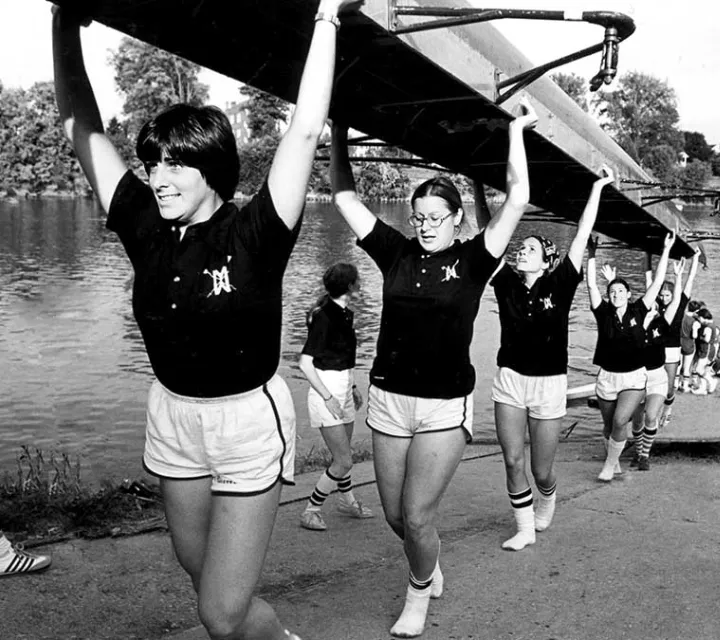 Black and white photo of the Marietta College women's rowing team carrying up their shell from the docks in 1970s