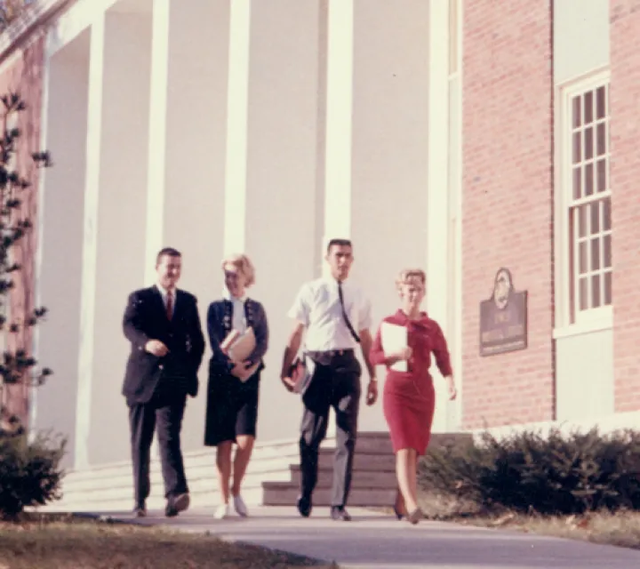 Photo of four students walking in front of the Dawes Memorial Library in the 1960s