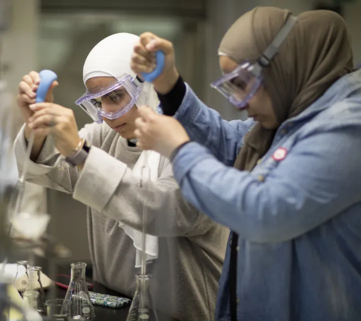 Marietta College chemistry majors using droppers and beakers in a chemistry lab inside Rickey Science Center.