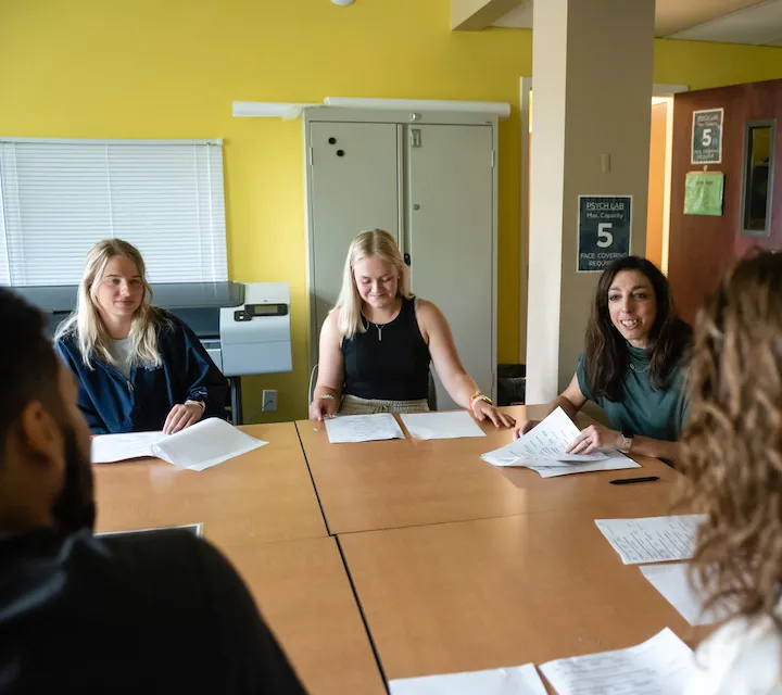 Students in the Marietta College Master of Arts in Psychology (MAP) Program sit around a table during a discussion with a professor.