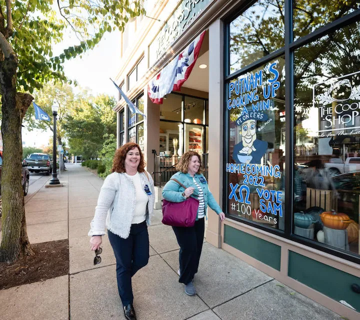 Two Marietta College Alumni walk past The Cook's Shop on Front Street in downtown Marietta