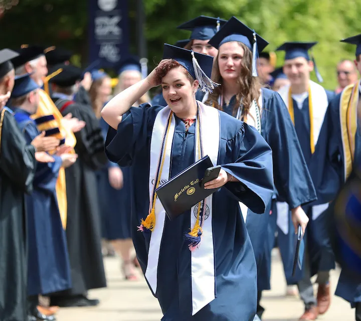 A Marietta College graduate walks in the post-commencement ceremony procession