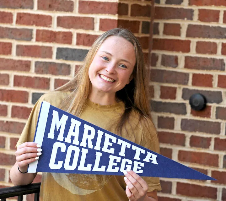 A Marietta College student holding a Marietta College pennant