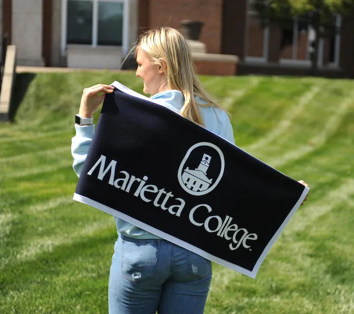 A Marietta College student holds a Marietta College flag/banner