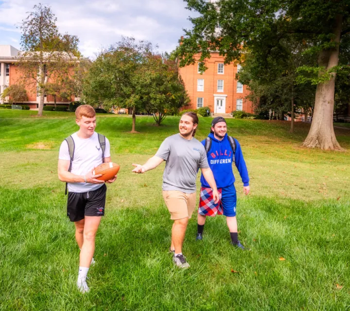 Three Marietta College student tossing a football around