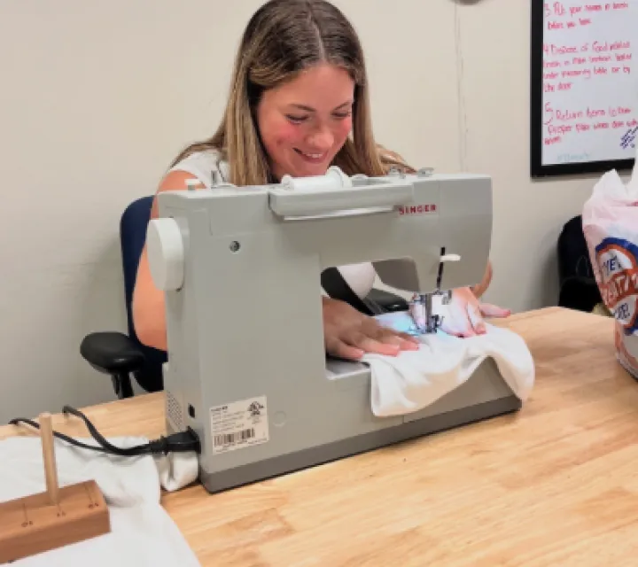 McDonough Scholar Brandice Kunze ’28 sews on a sewing machine