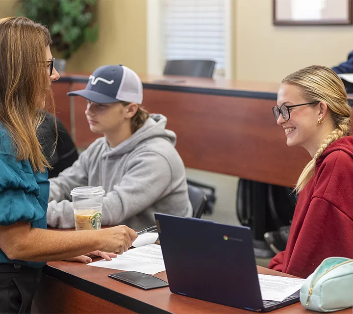 Professor and two students converse during class