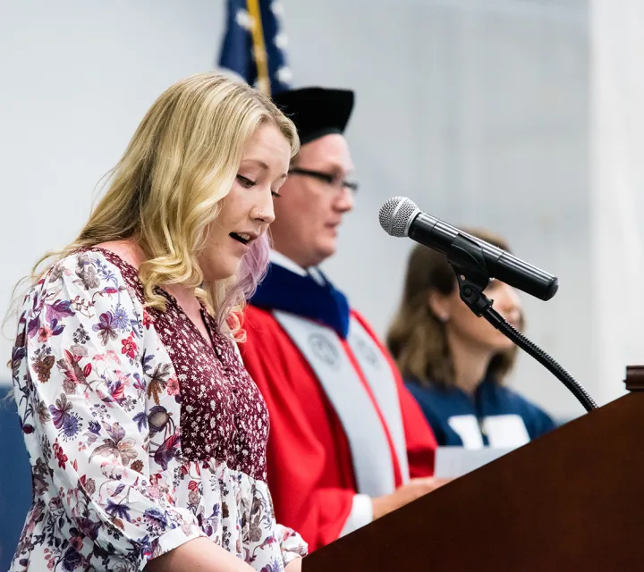 Female Student Sings Marietta College's Alma Matter at a Podium During Matriculation