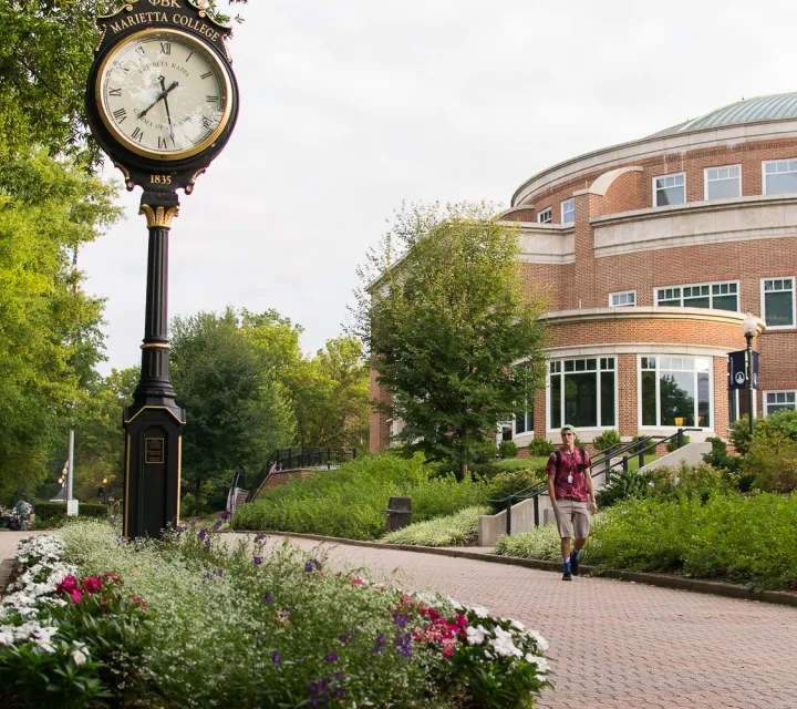 Student walks by clock on the Christy Mall