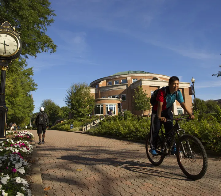 student rides bike down the mall