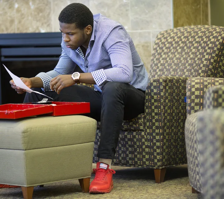 Student looks at papers in a lobby area