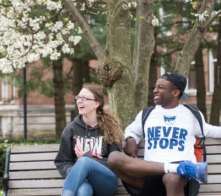 two students talking with a friend near the bell tower