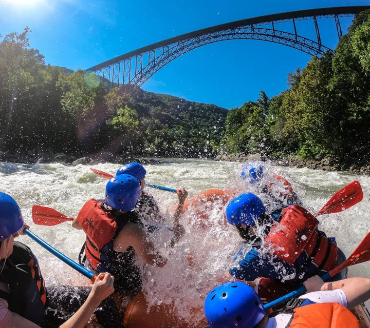 Students raft on the New River Gorge under a bridge