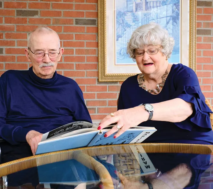 Marietta College Alumni Carl '64 and Judy '66 sit and look at an old yearbook together