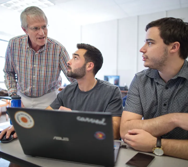 Two Marietta College students work with their professor in the classroom