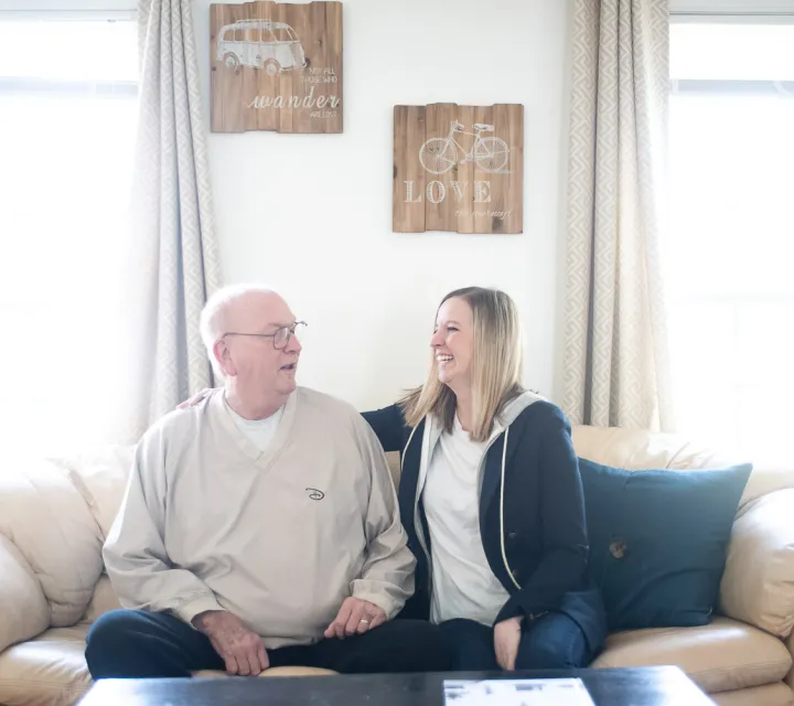 Hailee Stender '10 sits on a couch next to her father