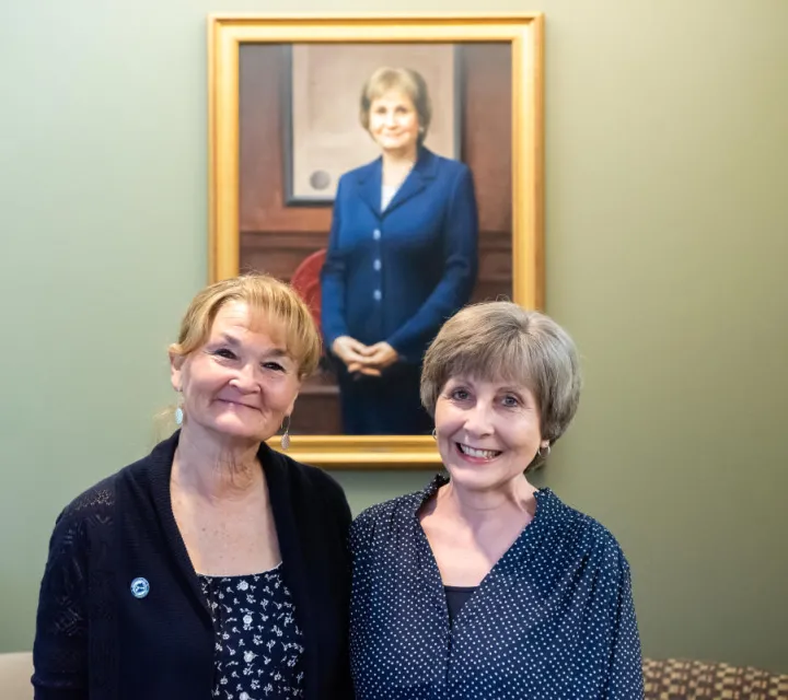 Linda Roesch and Linda Showalter Pose in front of the portrait of Jean Scott