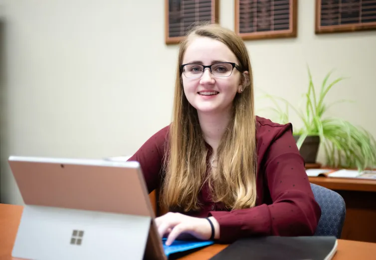 Student smiling with a tablet in front of her