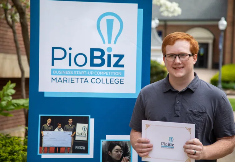Austin McCleary holding a certificate in front of a poster board