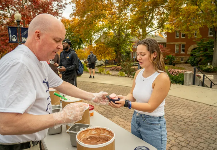 Marietta College's Tom Perry hands out ice cream to a student on the Christy Mall