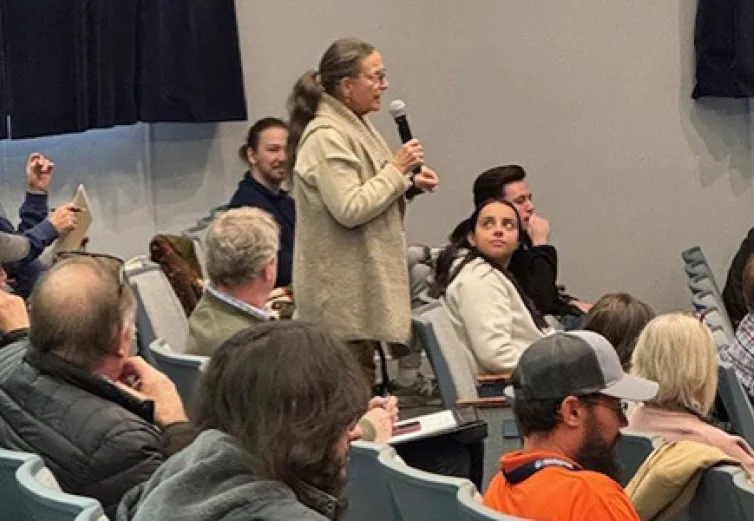 Ann audience member in McDonough Center Auditorium asks a question of the panel at the Timber sympoiium
