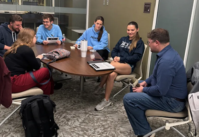 Students gather around a table with an advisor