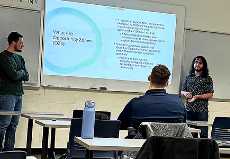 Two students present their research on Opportunity Zones to a fellow student