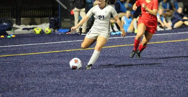 Women's soccer player kicking the ball